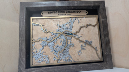 Framed topographic map of Estes Park, Colorado on a wooden surface.