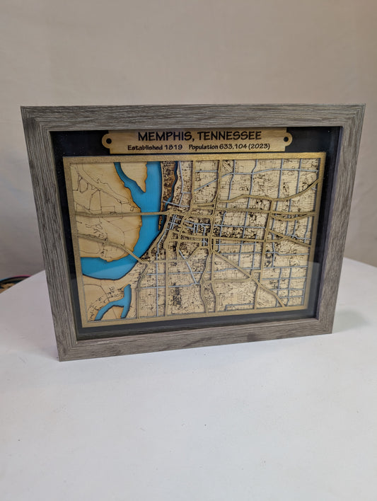 A framed laser cut map of Memphis Tennessee with a wooden border, displaying the city's streets and water bodies.